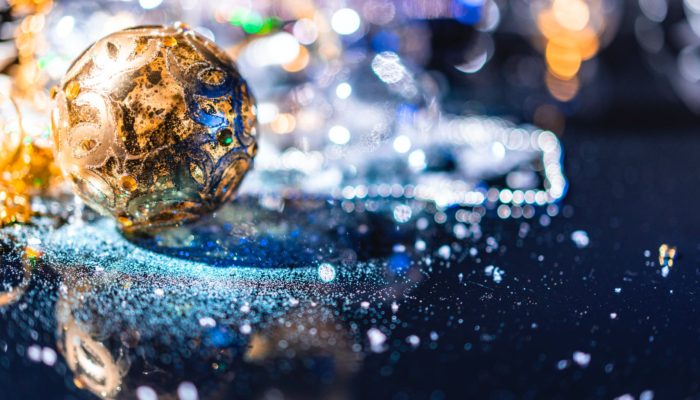 a gold christmas bauble on glass surface
