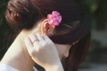 close up photo of a woman with pink flower on her ear